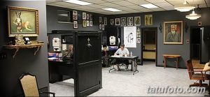 Фото тату-студии в классическом стиле с темными стенами, портретами и удобными креслами для клиентов.