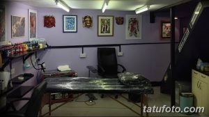 Фото тату-студии с удобным кушеткой для клиентов, полками с красками и эскизами, а также ярким освещением.