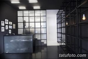 Фото минималистичной тату-студии с черными стенами, стеклянными перегородками и современным оборудованием. Идеальное место для тех, кто ценит лаконичность и чистоту.