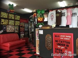 Фото интерьера тату-студии с яркими рисунками, красной мебелью и мультяшными персонажами.