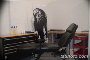 Фото минималистичной тату-студии с изображением волка на стене. Видны рабочее место мастера и оборудование.