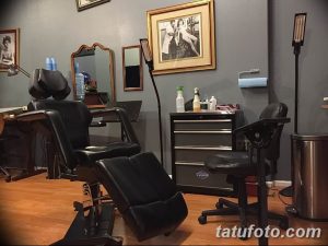 Фото просторной тату-студии с удобными креслами для клиентов и профессиональным оборудованием. Видны картины на стенах и хорошее освещение.