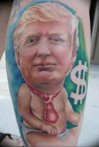 Фото тату: сатирический рисунок Дональда Трампа в подгузнике с долларовым знаком. Выражение политической позиции через татуировку.