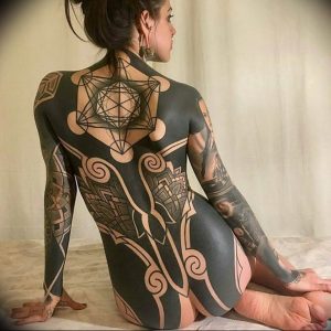 Фото тату: впечатляющая татуировка в стиле Blackwork, покрывающая всю спину и руки женщины сложными геометрическими узорами и символами.