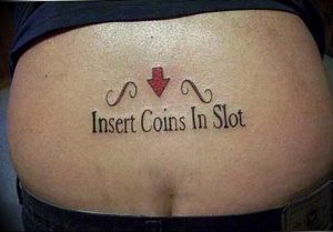 Фото татуировки с надписью "Insert Coins In Slot" и стрелкой на ягодицах. Дерзкий и юмористический рисунок.
