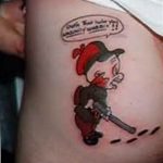 Фото тату на боку с изображением персонажа из мультфильма, держащего ружье, и надписью 'Get in there you nasty woman!!'.