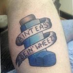 Необычная татуировка на руке с изображением ингалятора и надписи "Ain't Easy Bein' Wheezy".
