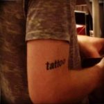 Фото тату на руке с надписью 'tattoo'. Простой шрифт и черные чернила делают рисунок минималистичным и стильным.