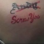 Фото тату на спине с надписью 'Screw You'. Рисунок выполнен красными чернилами и имеет слегка размытый вид.