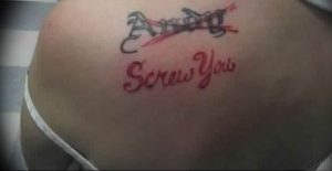 Фото тату на спине с надписью 'Screw You'. Рисунок выполнен красными чернилами и имеет слегка размытый вид.