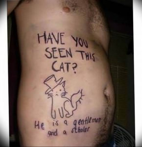 Фото тату на животе с изображением кота в шляпе и надписью 'Have You Seen This Cat? He is a gentleman and a scholar'. Юмористический дизайн.