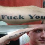 Фото тату с надписью 'Fuck You' черным цветом на предплечье. Простой шрифт, прямолинейный дизайн, вызывающий эпатаж.