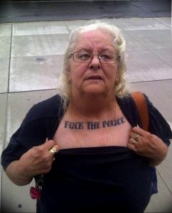 Фото татуировки на груди пожилой женщины с надписью "Fuck the Police".