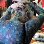 Фото тату на теле девушки: красочный рисунок в стиле акварель с изображением цветов, бабочек и абстрактных форм.