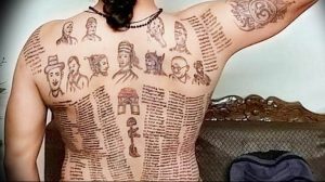 Фото тату: мужчина с татуировками, имитирующими страницы книги с текстом и иллюстрациями, покрывающими спину и плечи.