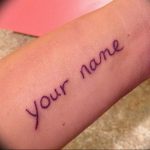 Фотография татуировки на запястье с надписью 'your name', выполненной простым шрифтом.