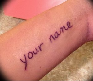 Фотография татуировки на запястье с надписью 'your name', выполненной простым шрифтом.