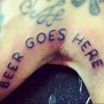 Шуточная татуировка на пальце с надписью 'BEER GOES HERE'. Черно-белый рисунок, выполненный небрежным стилем.