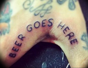 Шуточная татуировка на пальце с надписью 'BEER GOES HERE'. Черно-белый рисунок, выполненный небрежным стилем.