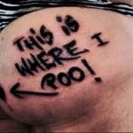 Татуировка на ягодицах с надписью 'THIS IS WHERE I POO!' и стрелкой, указывающей вниз. Необычный и вызывающий рисунок татуировки.