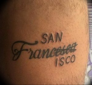 Черно-белая татуировка на руке с надписью 'San Francisco' выполненная каллиграфическим шрифтом. Минималистичный рисунок татуировки.