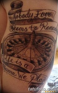 Фото татуировки на плече с изображением рулетки и надписью 'Nobody Ever Seems to Remember Life is a Game We Play'. Черно-белая графика.