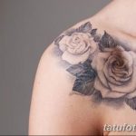 Фото тату: реалистичная татуировка с изображением двух роз, одна белая, другая серая, с зелеными листьями, расположенная на плече.
