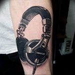 Фото тату на предплечье: детально прорисованные наушники SHURE, реалистичная передача текстур и теней. Современный дизайн татуировки.
