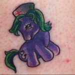 Фото тату на ноге: яркая и красочная татуировка в стиле мультфильма My Little Pony с изображением фиолетовой лошадки в медицинской шапочке.