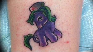 Фото тату на ноге: яркая и красочная татуировка в стиле мультфильма My Little Pony с изображением фиолетовой лошадки в медицинской шапочке.
