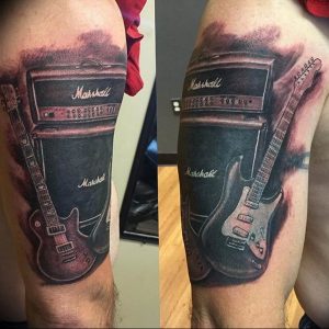 Фото тату гитары и усилителя Marshall на руке. Реалистичный черно-серый рисунок татуировки, демонстрирующий любовь к рок-музыке.