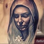 Фото тату изображения Богоматери в платке на руке. Детализированный рисунок в стиле реализм с акцентом на глаза и лицо.