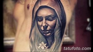 Фото тату изображения Богоматери в платке на руке. Детализированный рисунок в стиле реализм с акцентом на глаза и лицо.