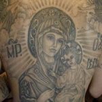 Фото массивной татуировки Богоматери на спине мужчины. Детализированный черно-серый рисунок с изображением Богоматери с младенцем Иисусом. Религиозная татуировка.