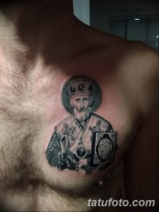 Фото тату Святого Николая Чудотворца на груди мужчины. Детализированный черно-серый рисунок с изображением святого в облачении и с книгой. Религиозная татуировка.