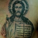 Фото тату иконы Иисуса Христа на плече. Детализированный рисунок с изображением Христа, нимба и древнерусской надписи. Черно-белая татуировка в религиозном стиле.