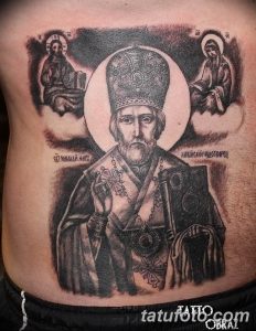 Фото тату Святителя Николая Чудотворца в черно-белом стиле на боку мужчины. Детализированный рисунок с изображением святого, нимба и надписей.