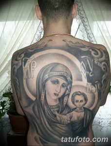 Фото большой татуировки Богоматери с младенцем Иисусом на спине. Черно-серый рисунок татуировки в религиозном стиле с детальной проработкой лиц и одежд.