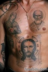 Фото тату Иисуса Христа и святых на груди мужчины. Черно-серый рисунок с изображением ликов святых и креста.
