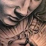 Фото татуировки Богоматери с четками на руке, выполненной в черно-серых тонах. Изображение имеет детализированный и реалистичный вид.