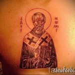 Фото тату Святого Николая Чудотворца на груди, выполненное в черно-серых тонах. Изображение заключено в круг с надписями на старославянском языке.