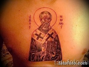 Фото тату Святого Николая Чудотворца на груди, выполненное в черно-серых тонах. Изображение заключено в круг с надписями на старославянском языке.
