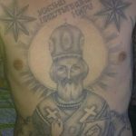 Фото тату Святого Николая Чудотворца на груди, выполненное в черно-серых тонах. Изображение отличается традиционной иконографией и сложной детализацией.