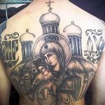 Фото тату Богоматери с младенцем на фоне собора, выполненное в черно-серых тонах. Изображение размещено на спине и отличается сложной композицией.