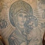 Фото татуировки с изображением иконы Богоматери с младенцем Иисусом, выполненной в традиционном стиле с использованием ярких цветов и золотых акцентов.