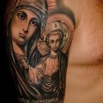 Фото татуировки с изображением иконы Богоматери с младенцем Иисусом, выполненной в ярких цветах с использованием золотых акцентов.