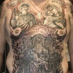 Фото тату на груди и животе с изображением нескольких религиозных фигур и символов. Рисунок татуировки выполнен в черно-белой гамме.