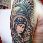 Фото тату на плече с изображением Богоматери с младенцем Иисусом. Рисунок татуировки выполнен в реалистичном стиле с использованием мягких оттенков.
