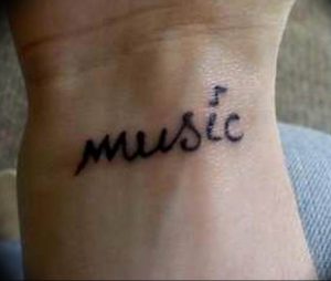 Фото тату надписи 'music' на запястье, выполненной черными чернилами. Простой и элегантный рисунок татуировки для любителей музыки.