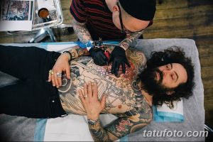 Фото процесса нанесения татуировки в японском стиле на спину мужчины. Мастер тату работает над деталями рисунка.